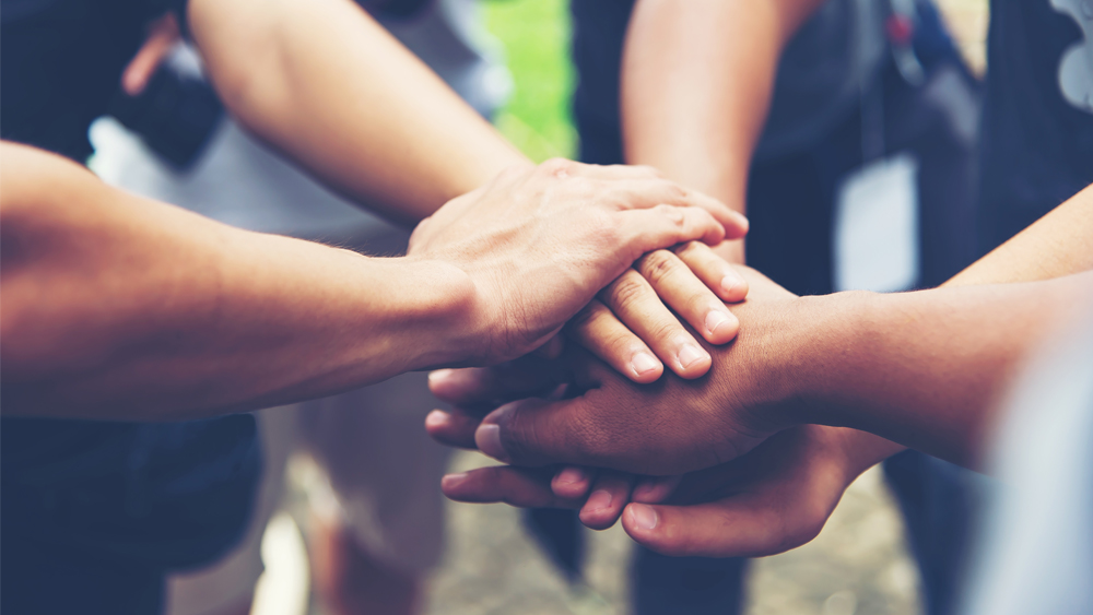 The palms of people of different colours overlap.