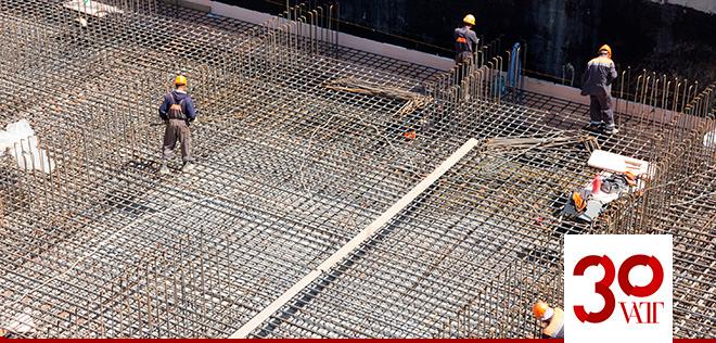 Työntekijöitä rakennustyömaalla. VATT 30 vuotta logo.